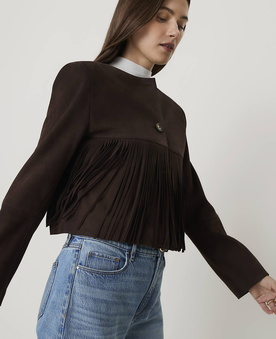 Brown fabric with fringe and buttons in the foreground is set against a blurred background.