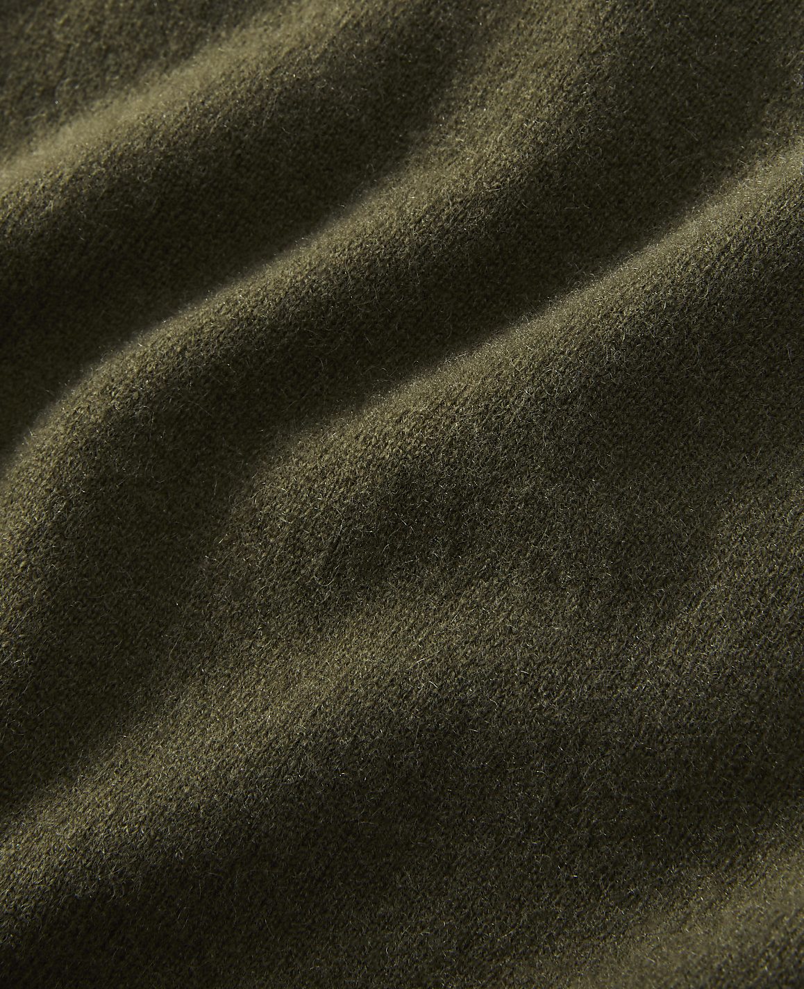 A close-up of olive green fabric with soft folds fills the frame, creating a textured and muted background.