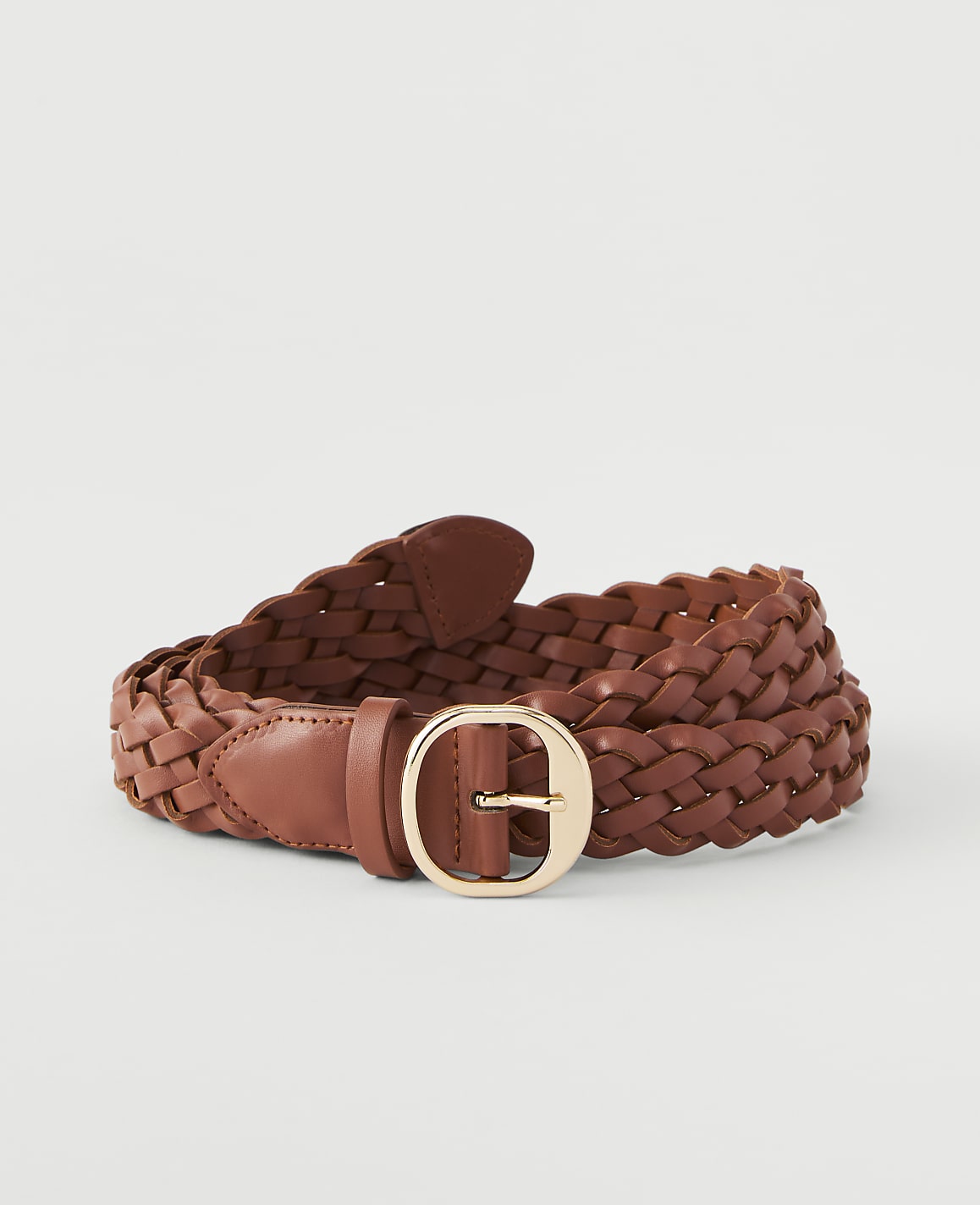 A braided brown leather belt with a gold buckle lies on a plain white background.