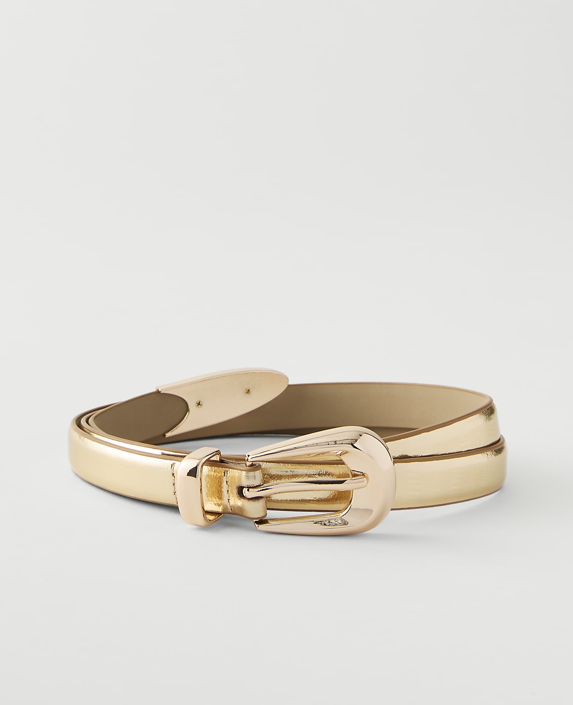 A shiny gold belt with a matching buckle lies on a plain white background.