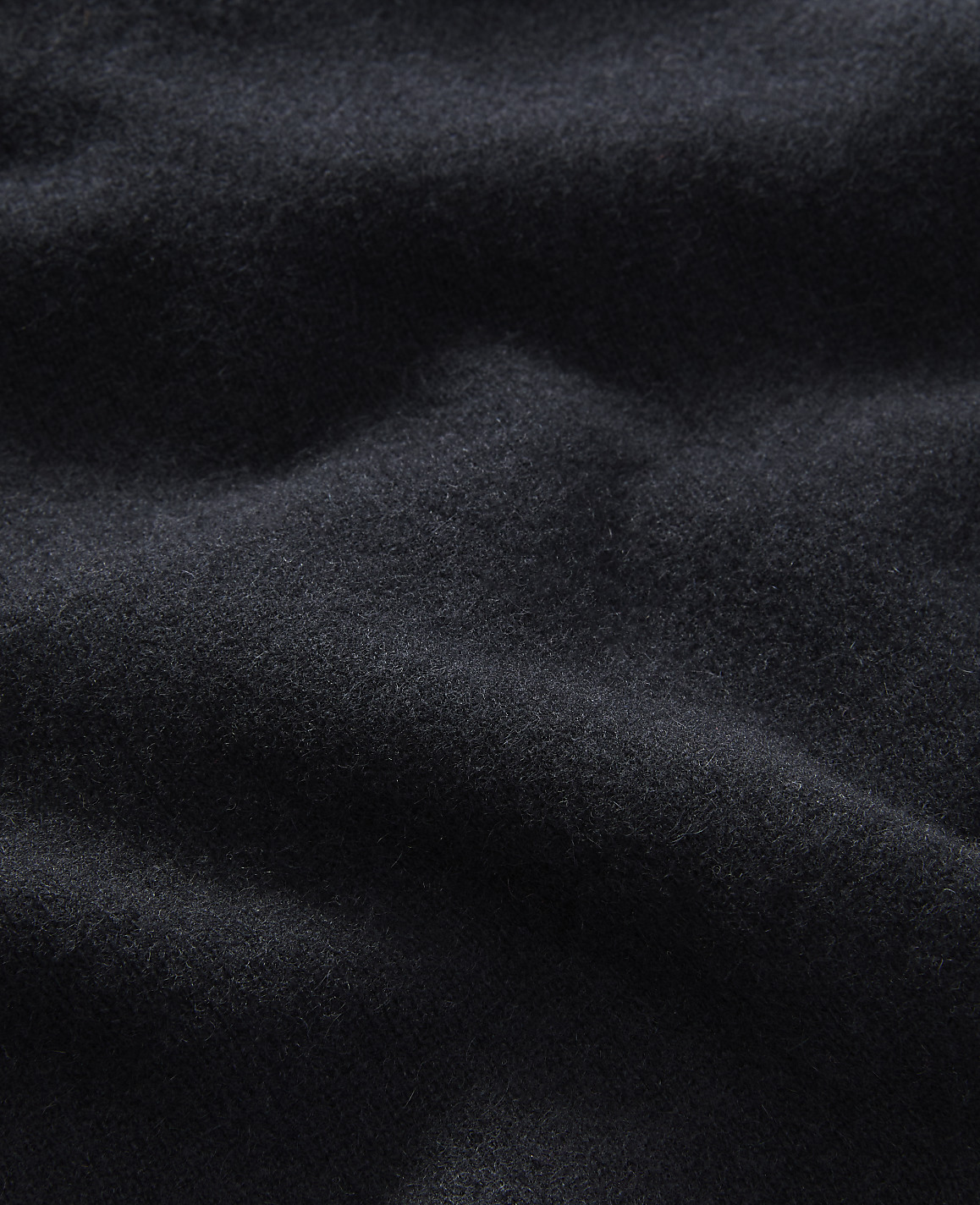 A dark, textured fabric with soft folds fills the frame, creating a sense of depth and shadow.