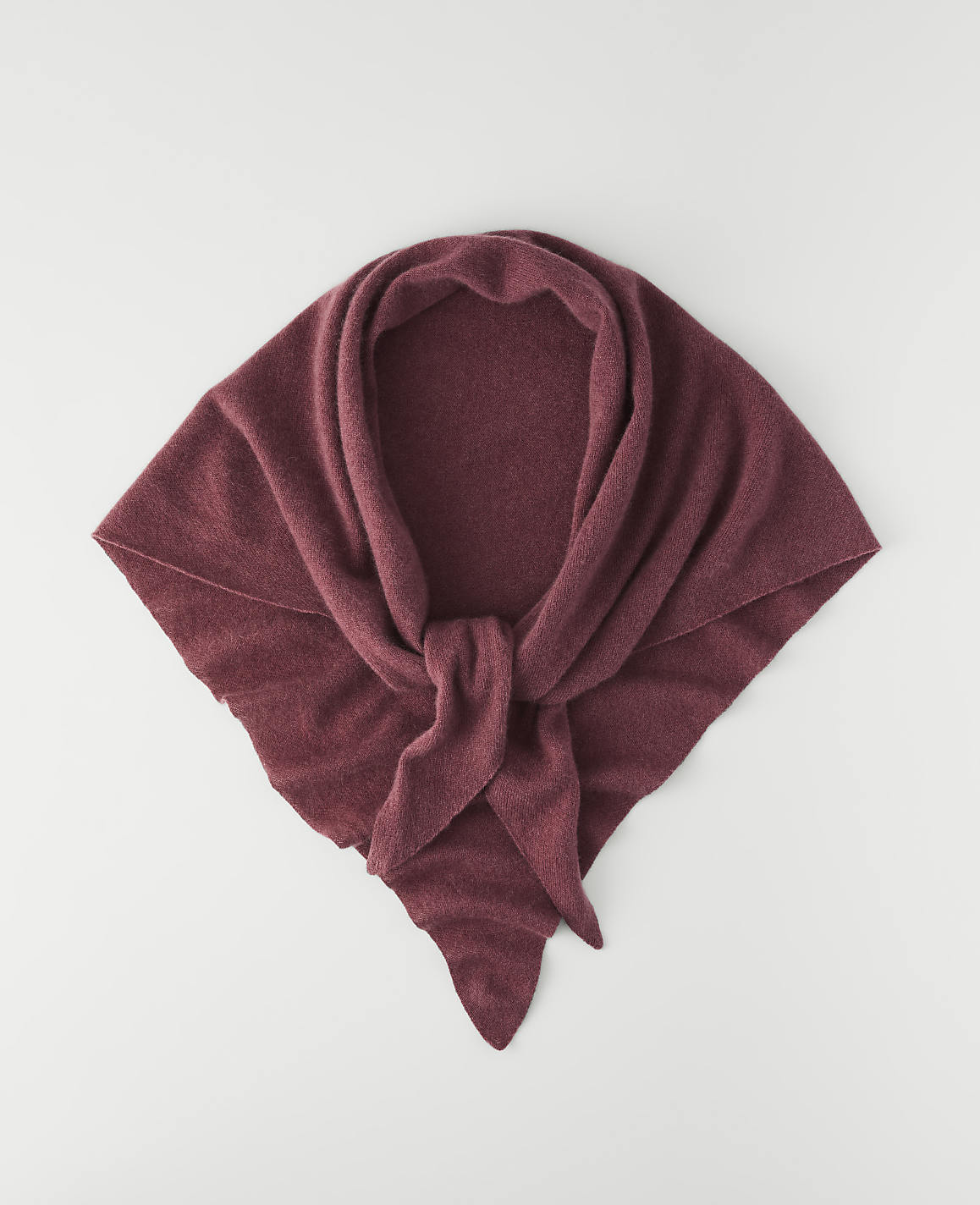 A maroon knitted scarf is laid flat on a white background.
