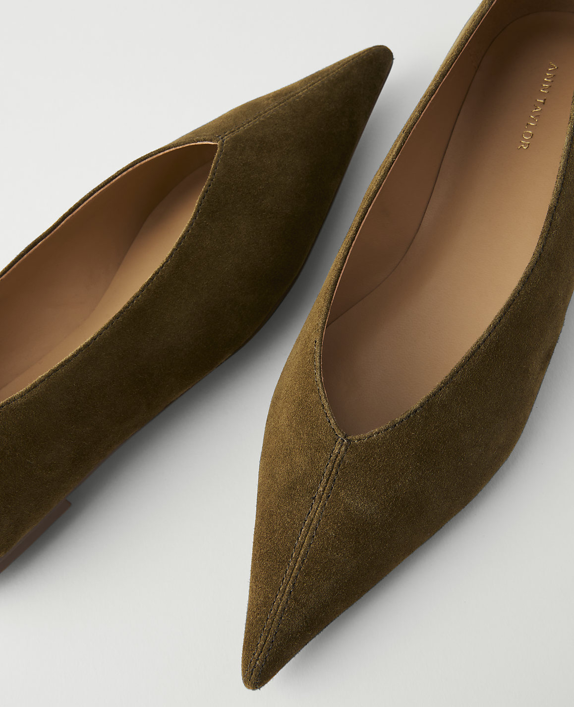 Two olive green suede pointed-toe flats are arranged on a white background.