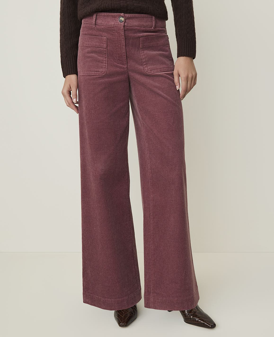 A person wearing wide-leg corduroy pants stands against a plain, light-colored background.