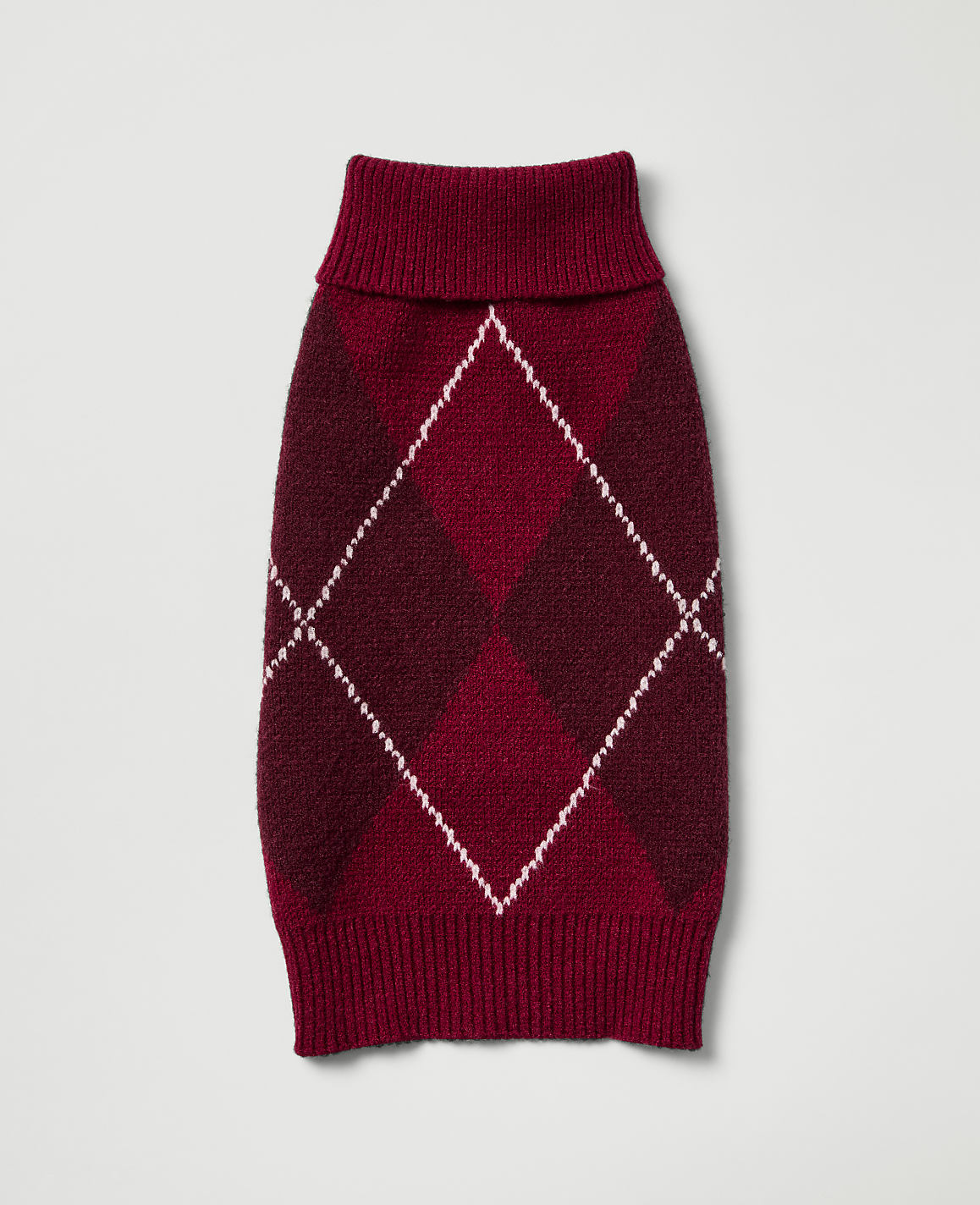 A burgundy argyle dog sweater with a ribbed collar and hem lies flat against a plain, light gray background.