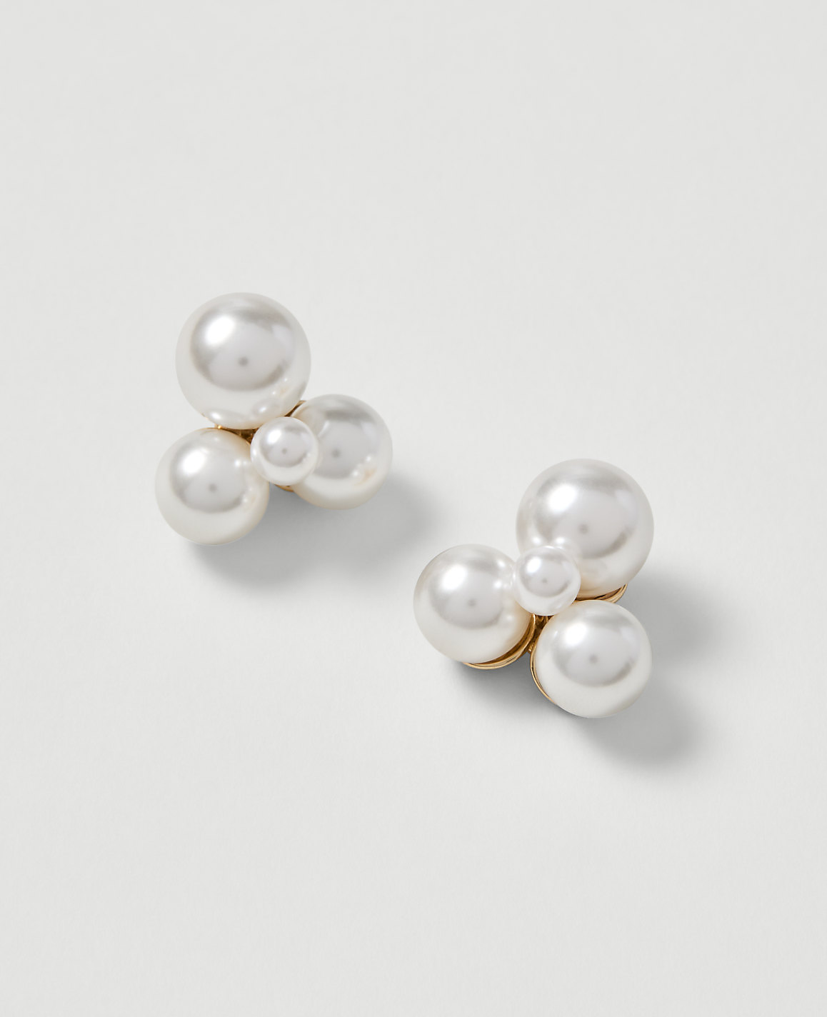 A cluster of pearl earrings rests on a plain white background.