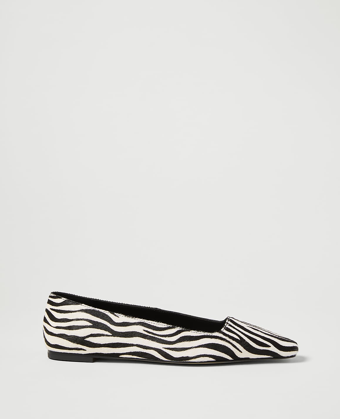 A zebra-print flat shoe rests on a plain white background.