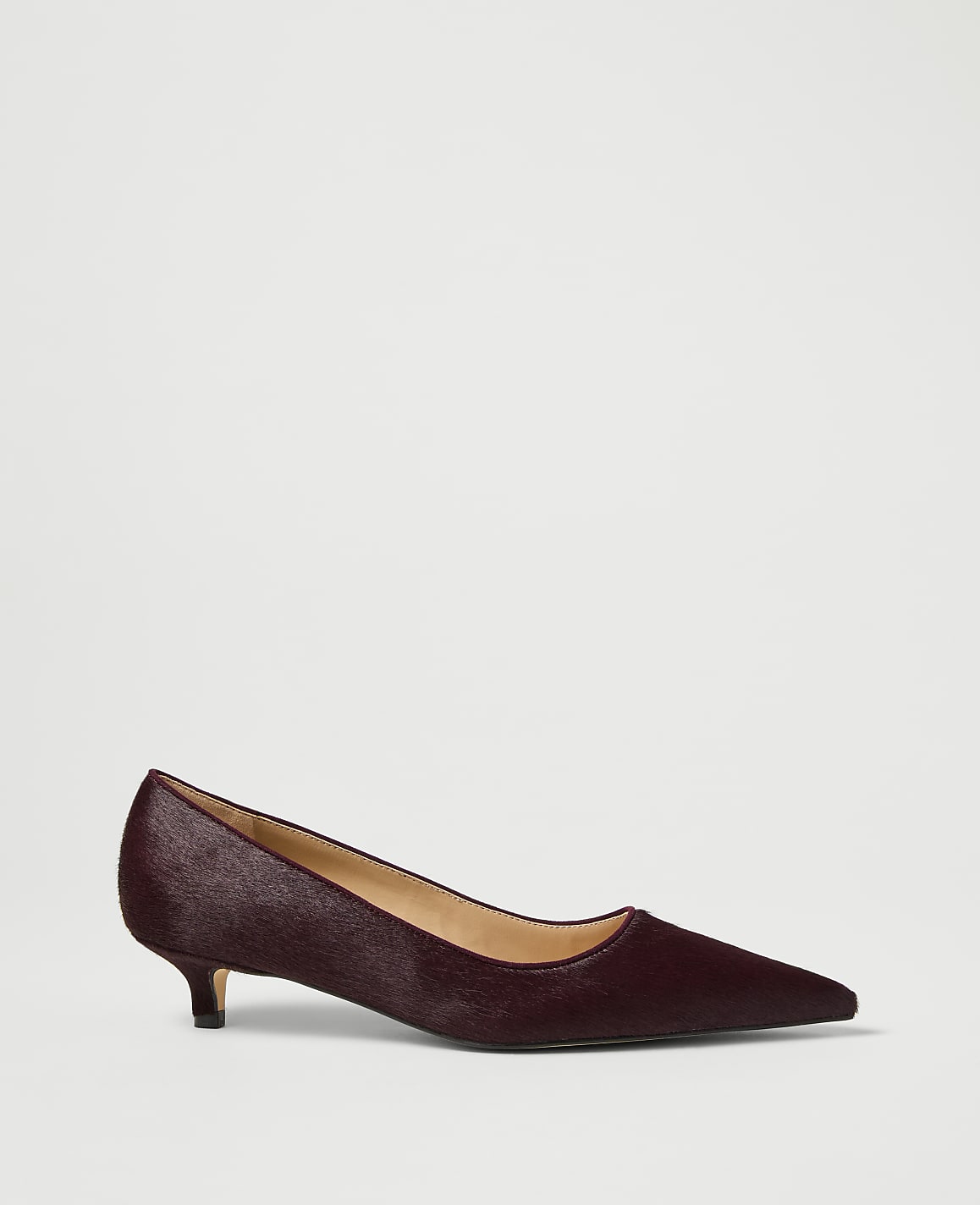 A burgundy, pointed-toe kitten heel shoe with a textured finish rests on a plain white background.