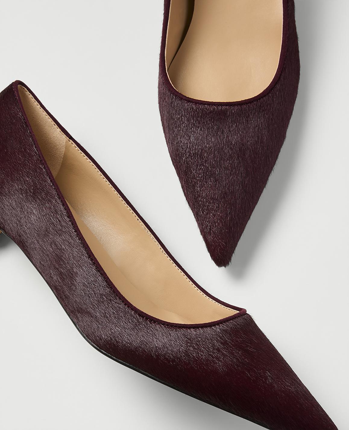 A pair of burgundy, pointed-toe pumps with a textured, furry finish are displayed against a plain white background.