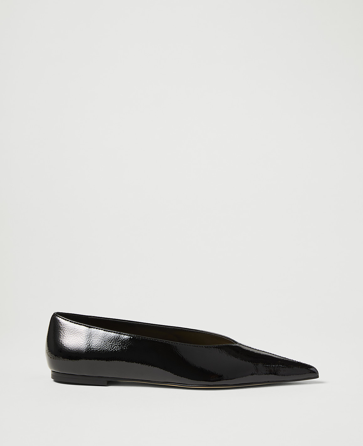 A glossy black pointed-toe flat shoe rests on a plain white background.