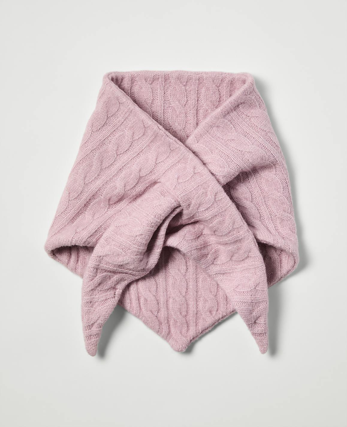 A pink cable-knit scarf is folded into a triangular shape against a plain white background.