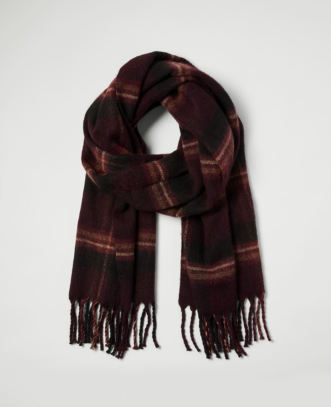 A burgundy plaid scarf with fringe hangs against a plain white background.