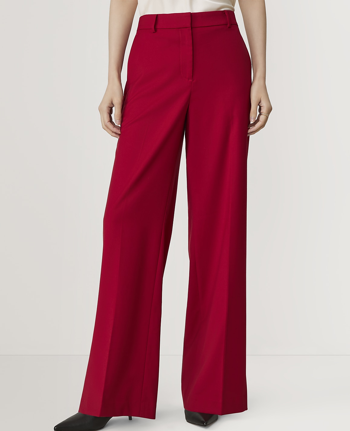 A person in bright red wide-leg trousers stands against a plain white background.