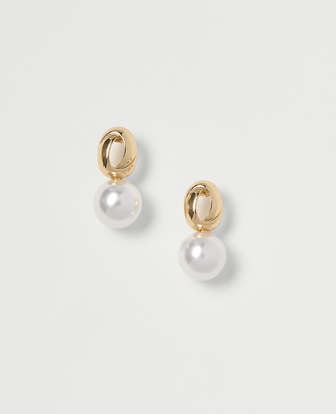 A pair of gold and pearl drop earrings are displayed against a plain white background.