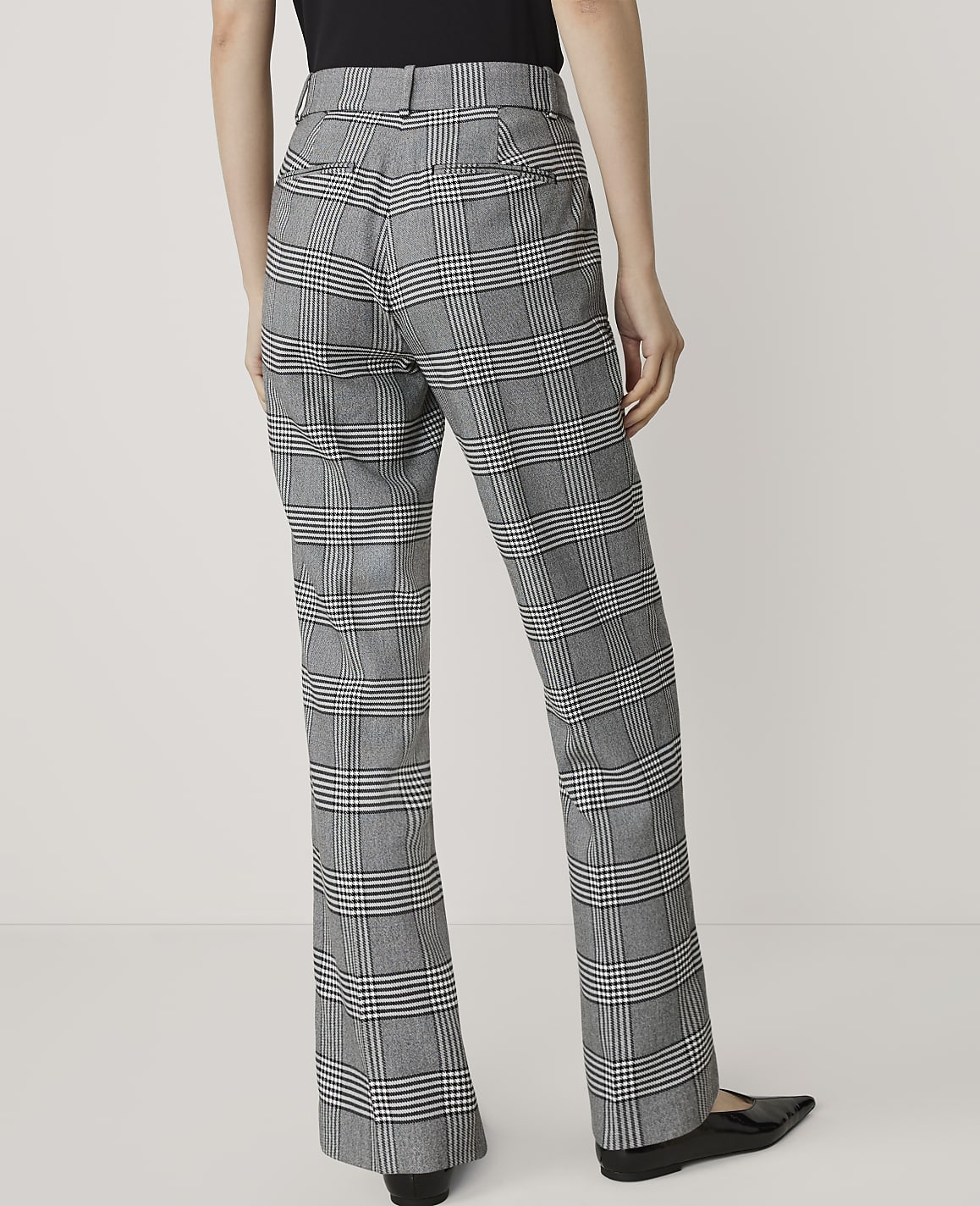 A person wearing plaid pants stands against a plain white background.