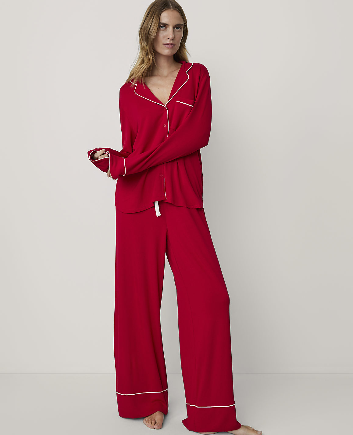 A woman in red pajamas stands against a plain white background.