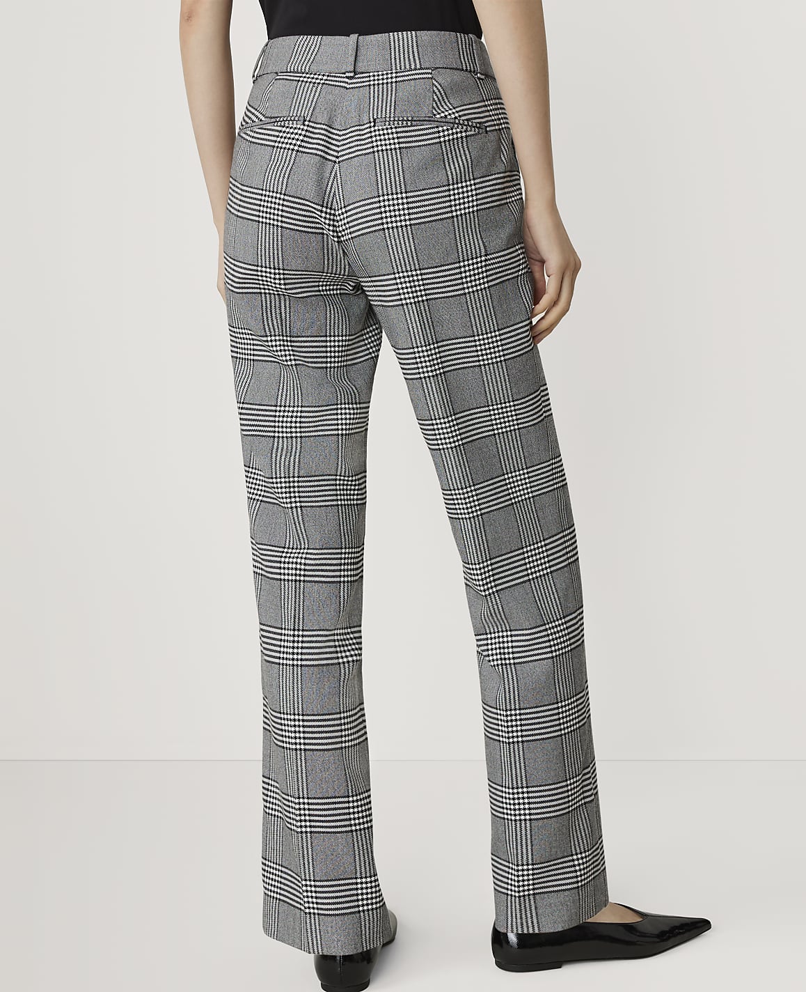 A person wearing plaid pants stands against a plain white background.