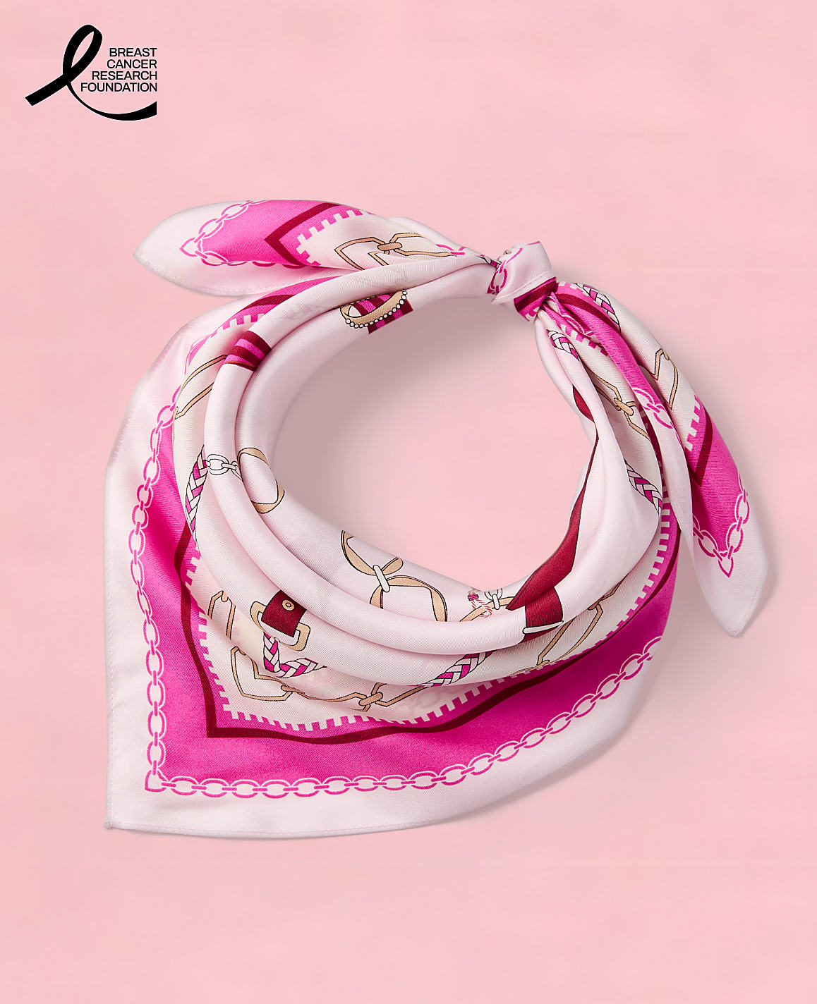 A pink silk scarf with a chain and anchor pattern is tied in a knot against a white background.