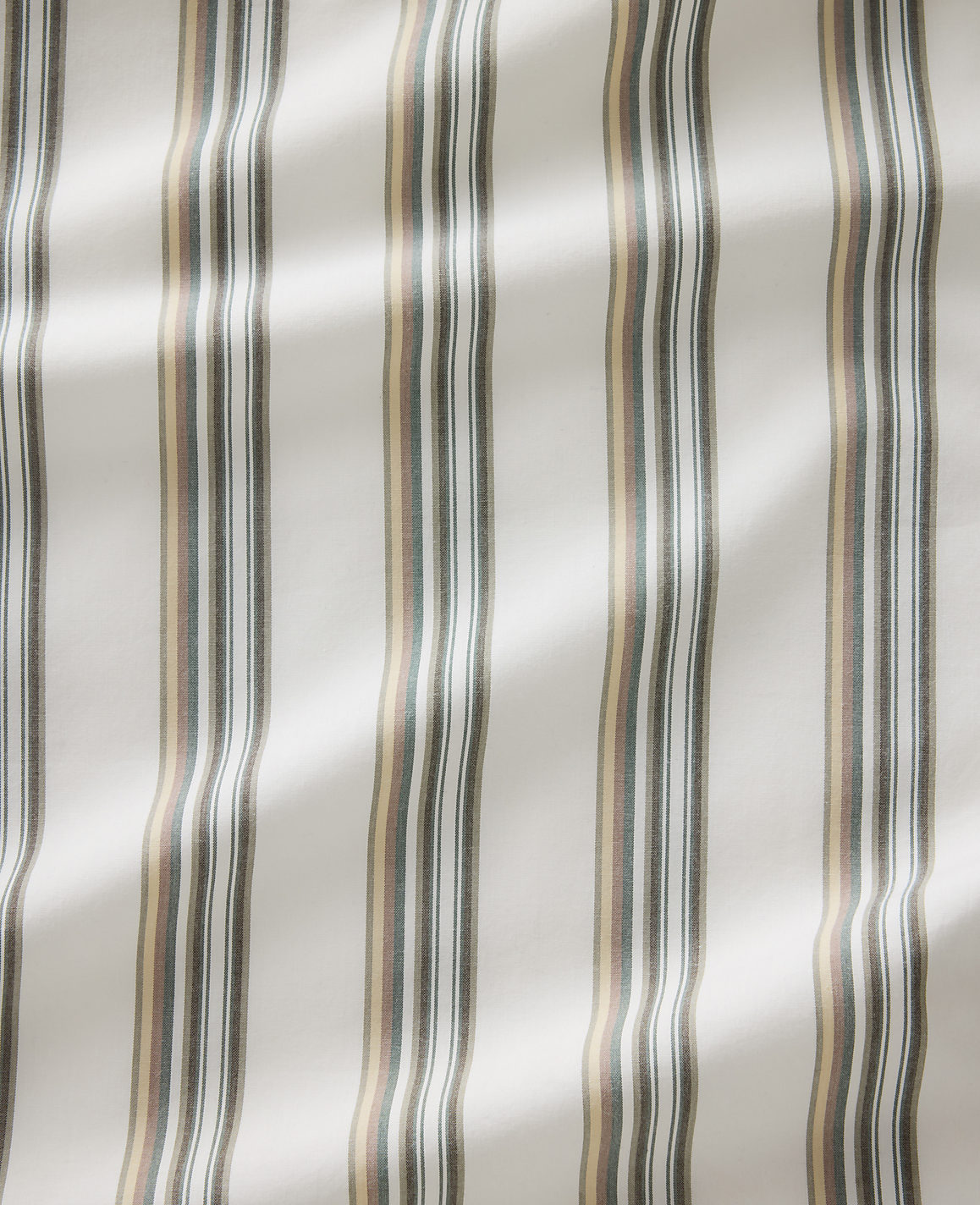Vertical stripes of cream, brown, and gray fabric are visible in the foreground, with soft lighting creating subtle shadows and highlights in the background.