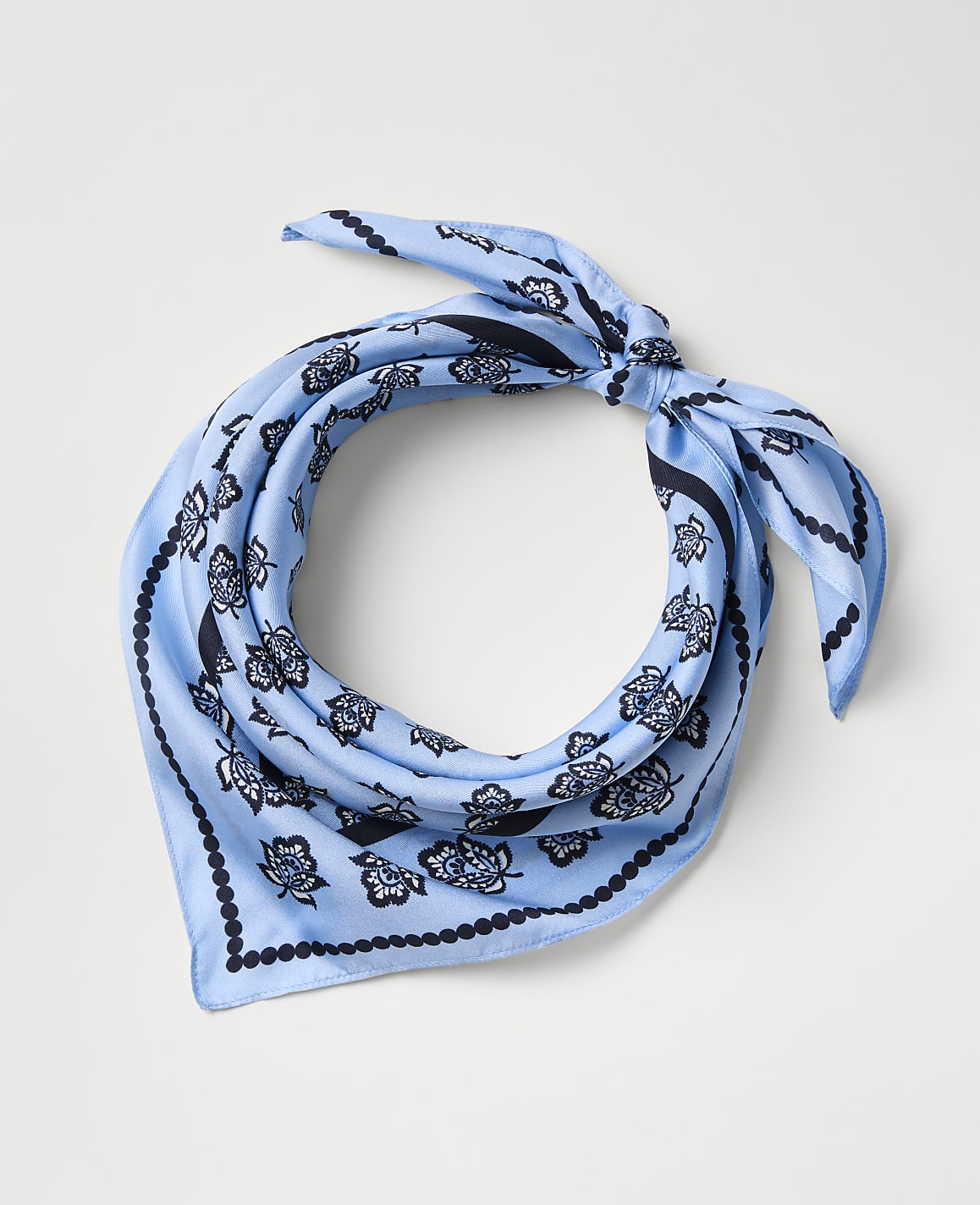 A light blue patterned bandana is tied in a knot against a plain light gray background.