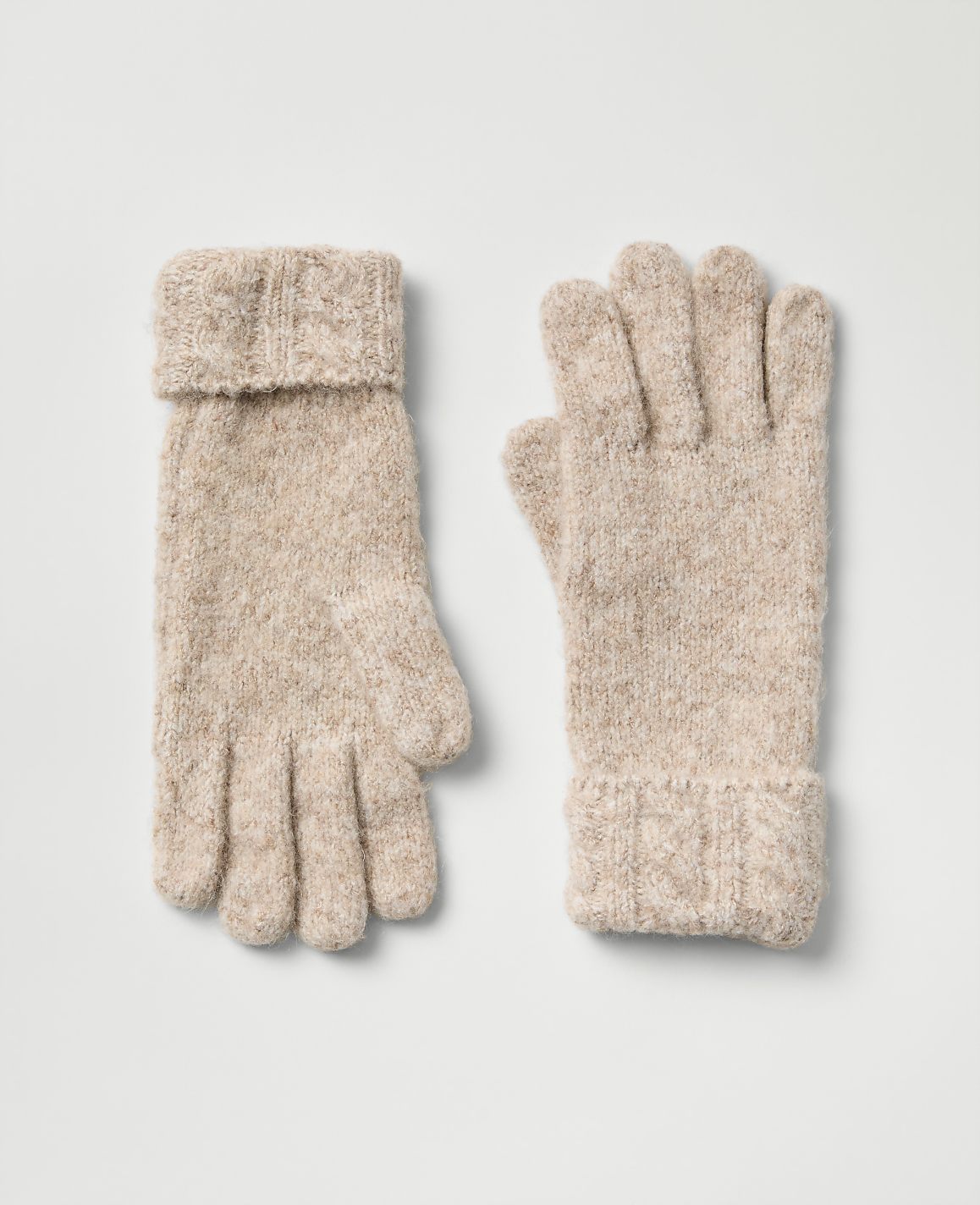 A pair of beige knitted gloves lies flat against a plain light gray background.