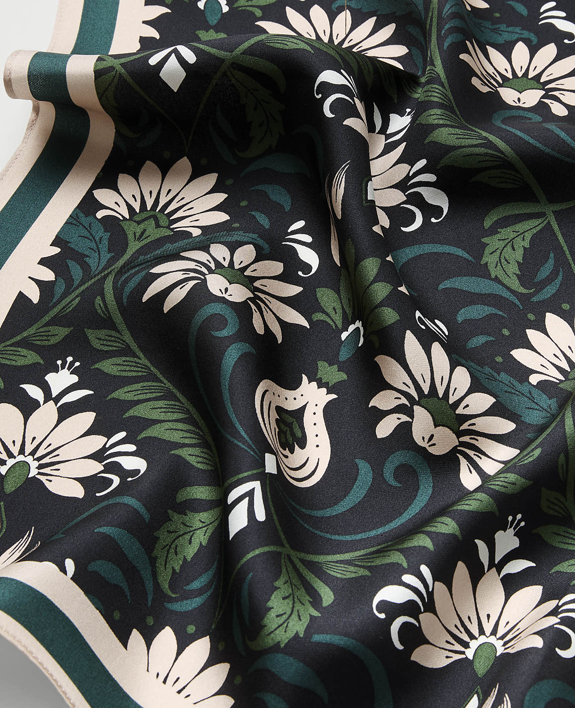 A draped black fabric featuring cream and green floral patterns in the foreground, with a matching patterned border visible in the background.