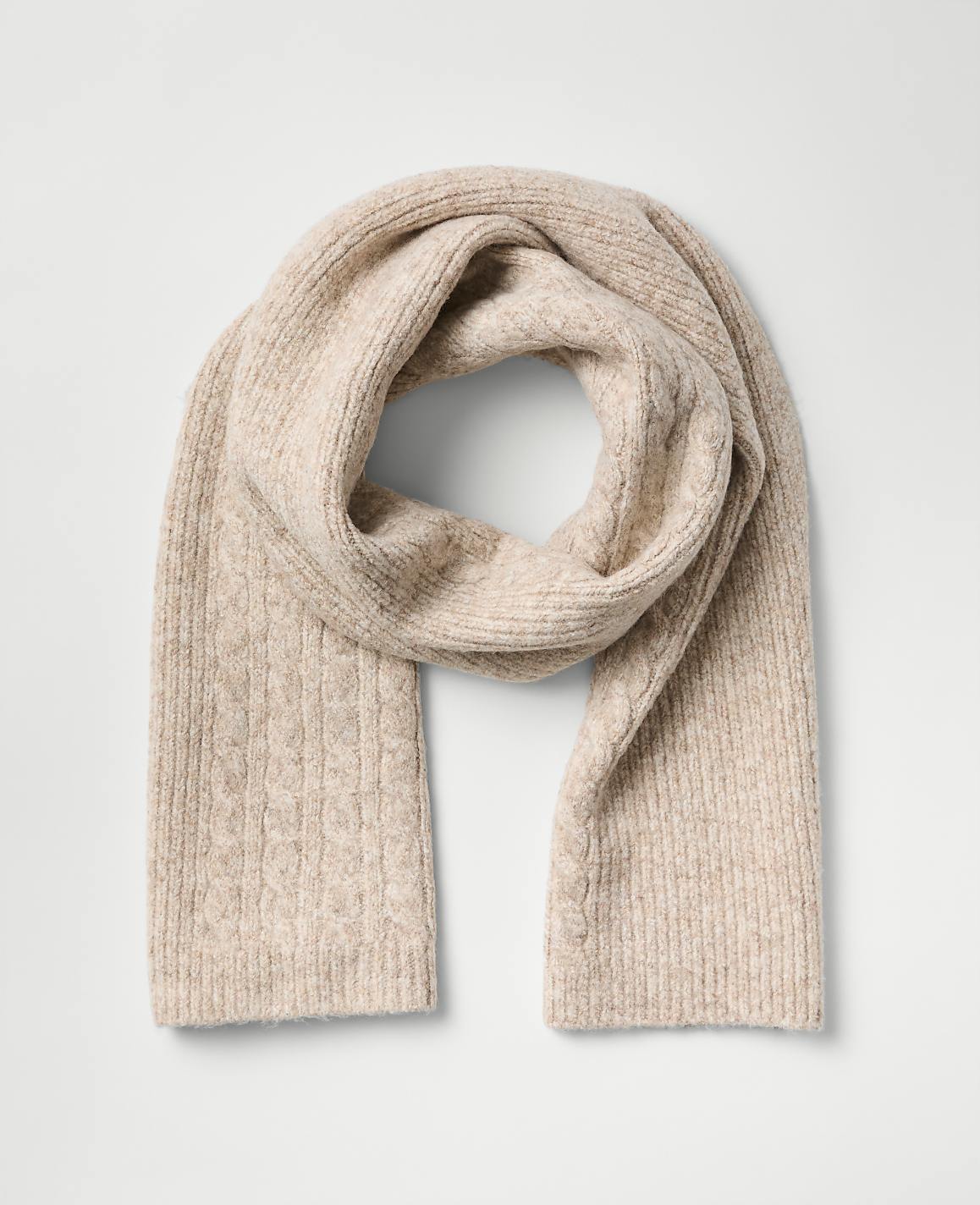 A beige ribbed knit scarf is draped in a loop against a plain light gray background.