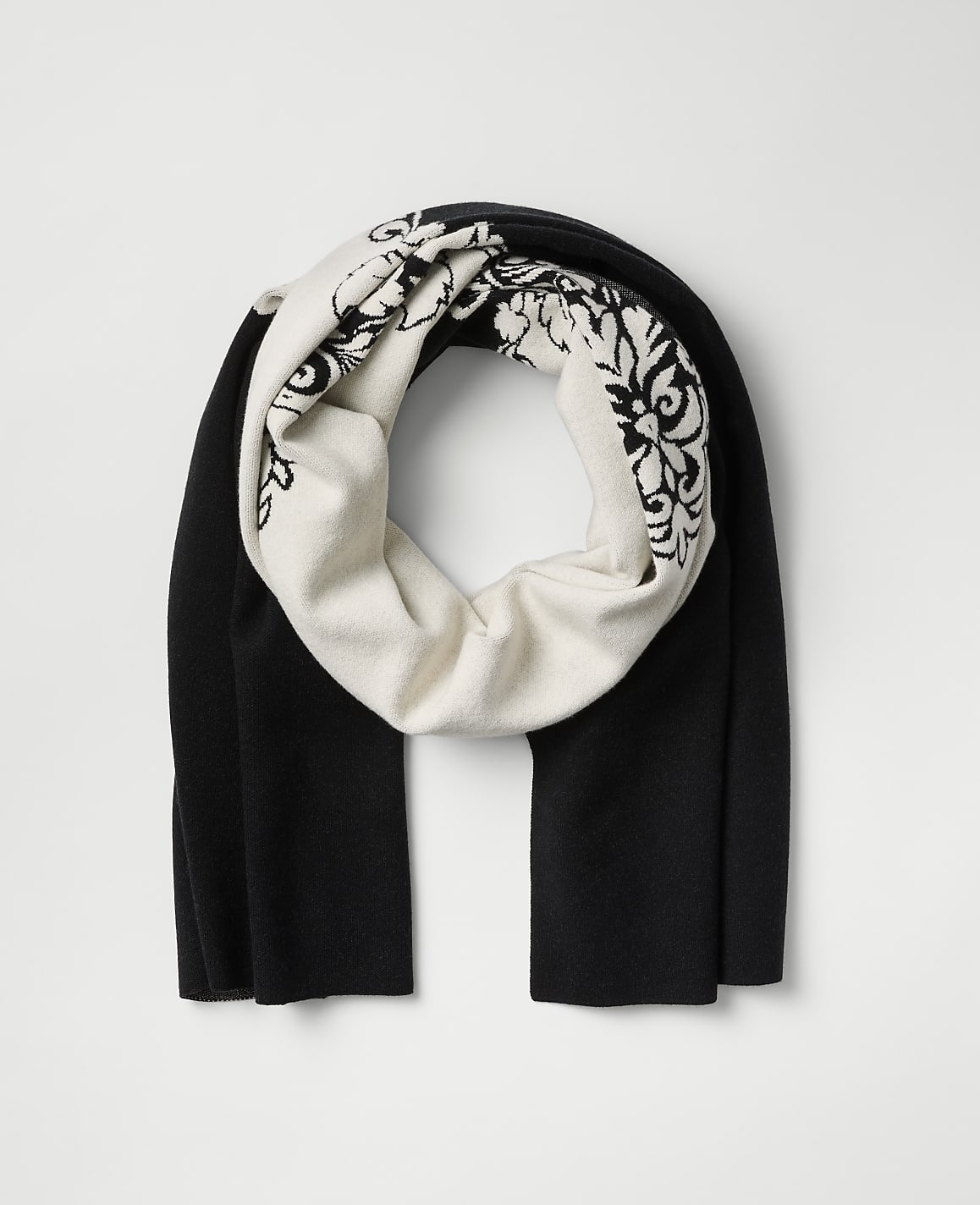 A black and white patterned scarf is centered against a plain light gray background.