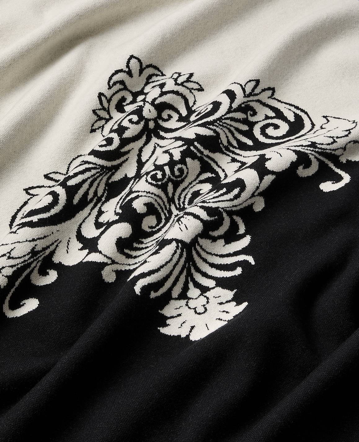 A black and white ornate damask pattern is woven into a draped fabric.