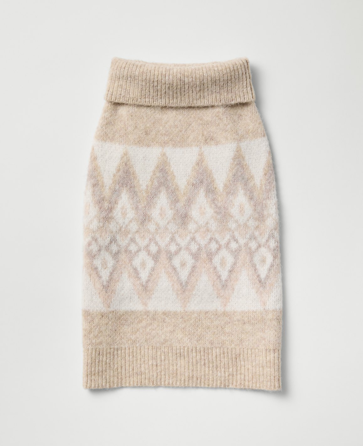 A beige and white patterned knit dog sweater lies centered against a plain, light gray background.