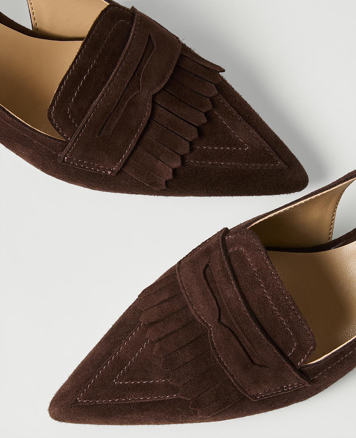 Two brown suede fringed loafers are positioned diagonally against a plain white background.