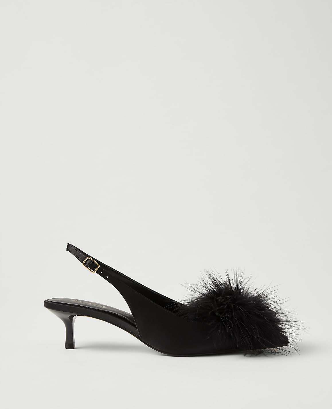A black satin slingback heel with a fluffy feather pompom on the toe sits against a plain light gray background.