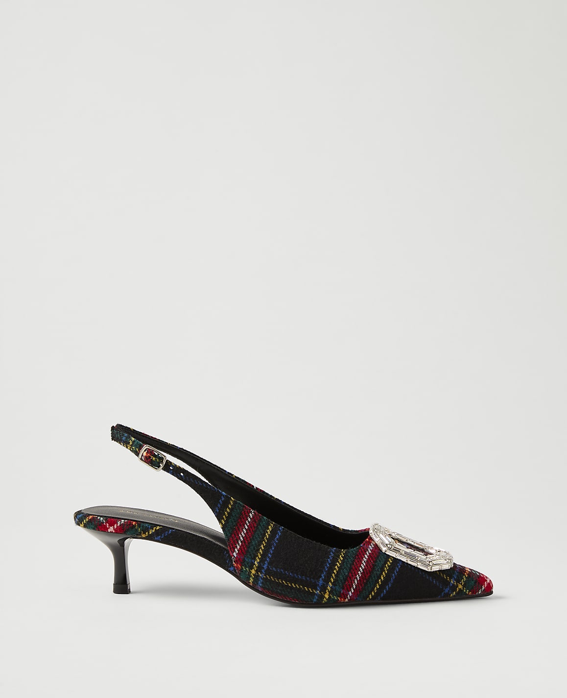 A plaid slingback heel with a crystal buckle sits against a plain, light gray background.