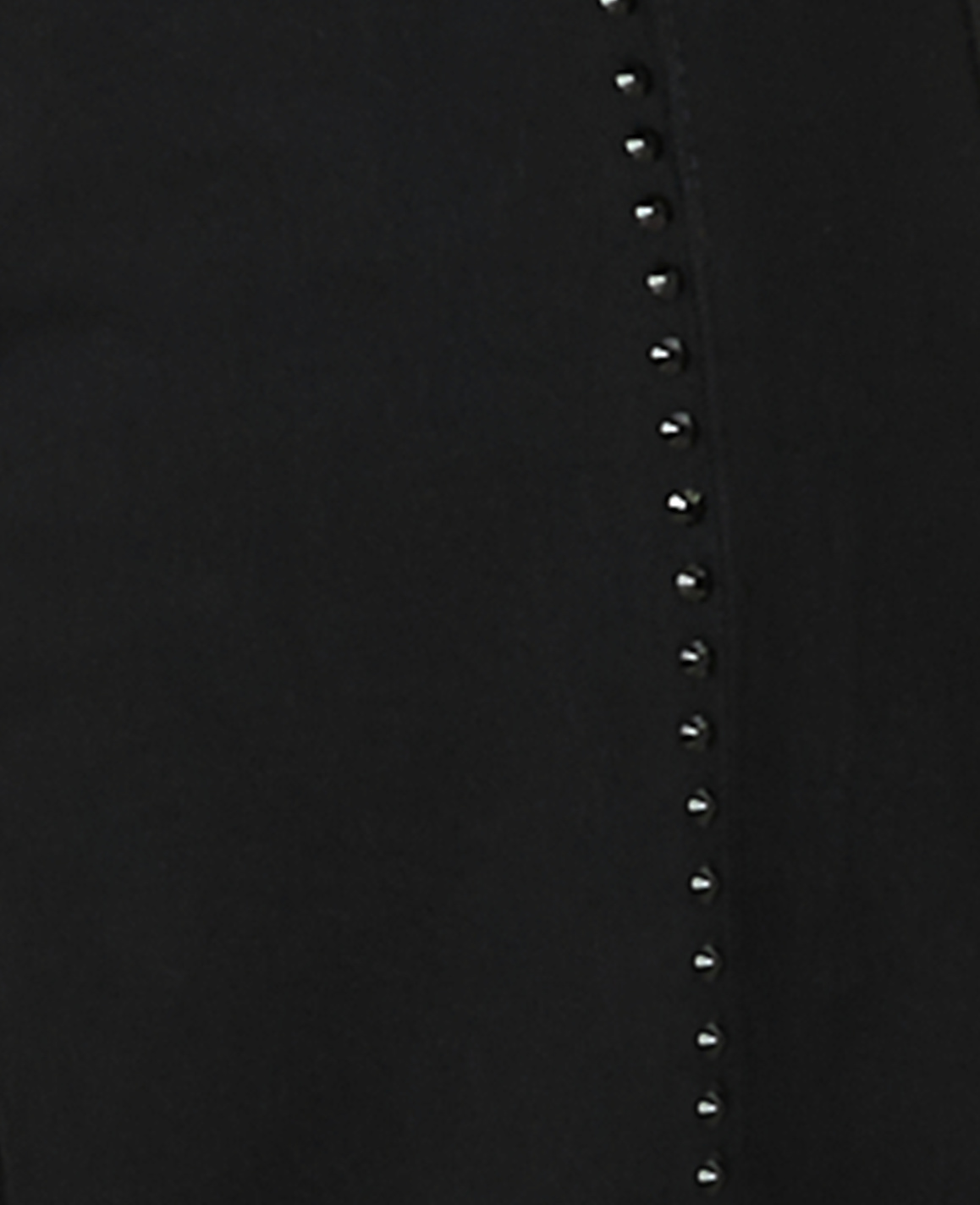 A vertical row of small, shiny studs runs down a black fabric background.