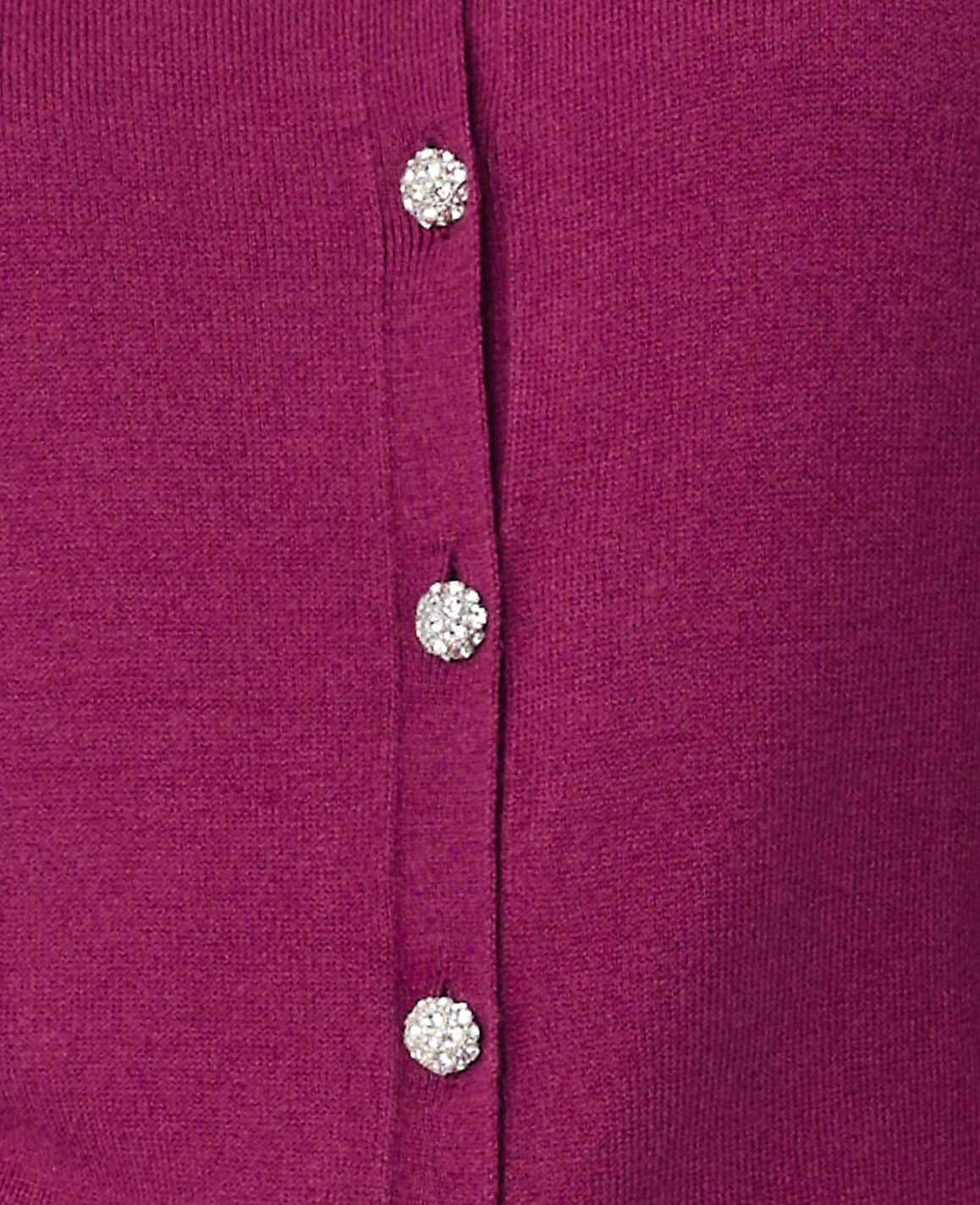 Three sparkling rhinestone buttons are aligned vertically on a magenta knit fabric.