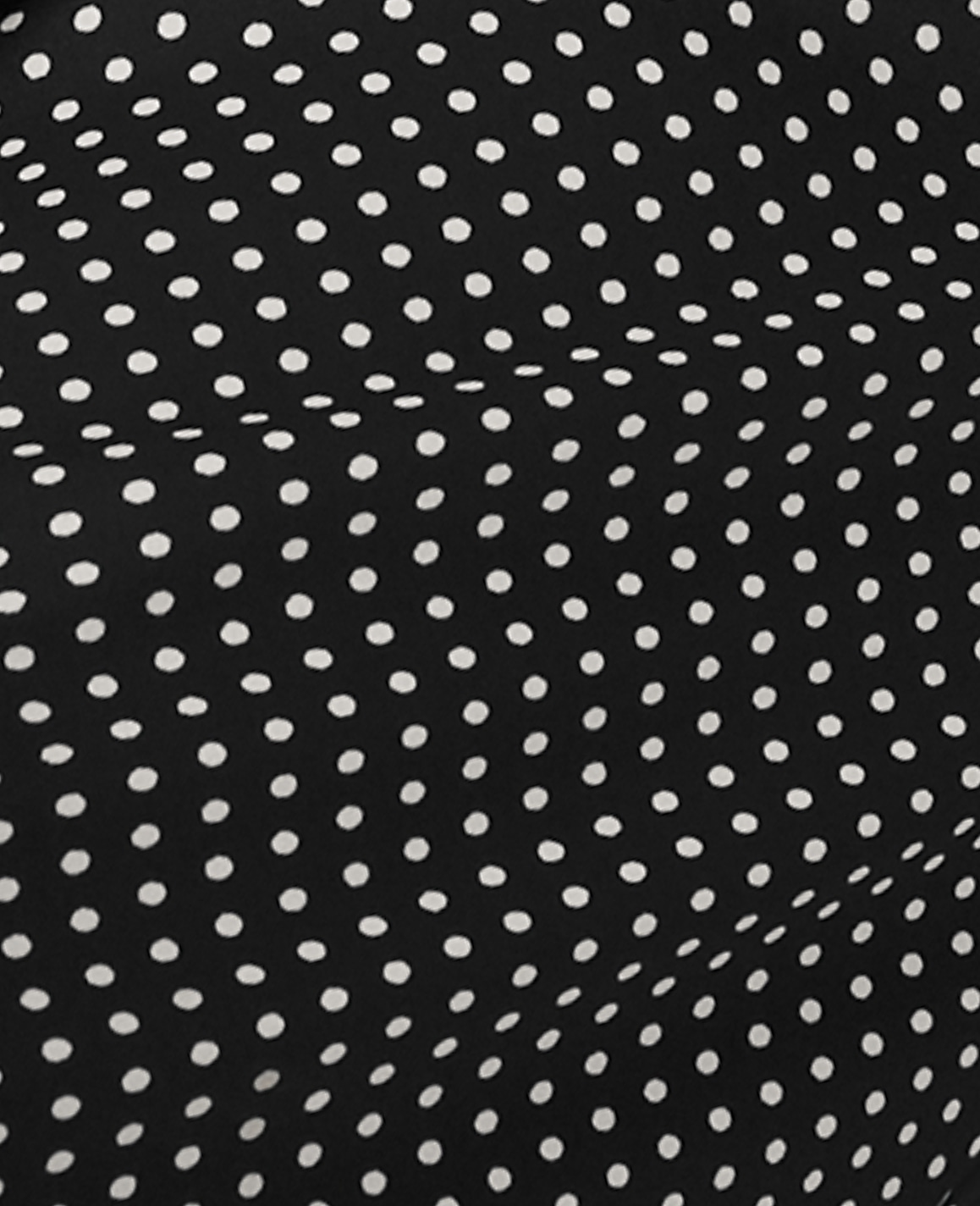 Small white polka dots are evenly spaced across a draped black fabric background.
