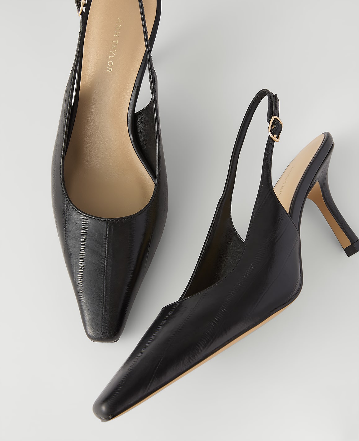 A pair of black pointed-toe slingback heels rests on a plain white background.