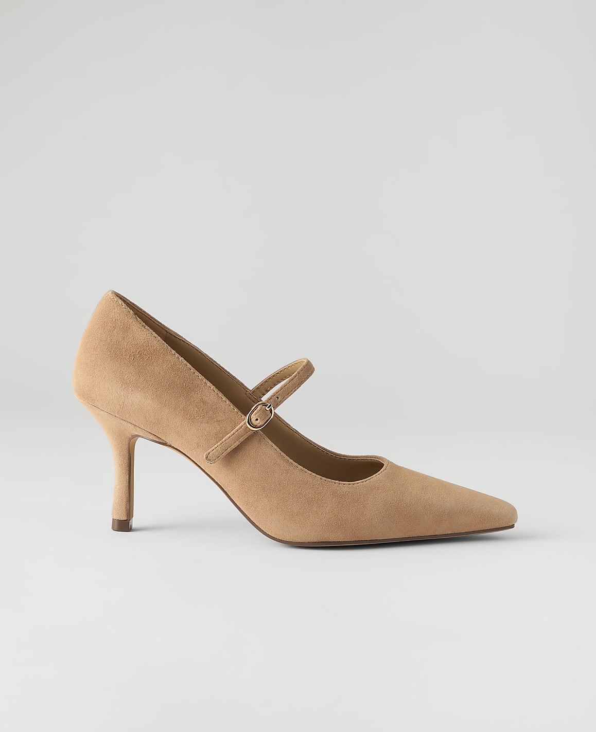 A tan suede pointed-toe pump with a strap sits against a plain, light gray background.