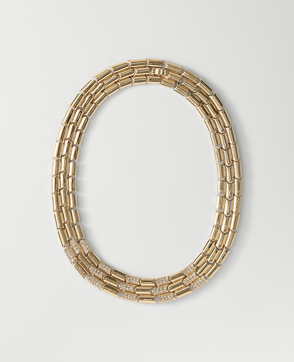 A gold link necklace with diamond accents rests on a plain white background.