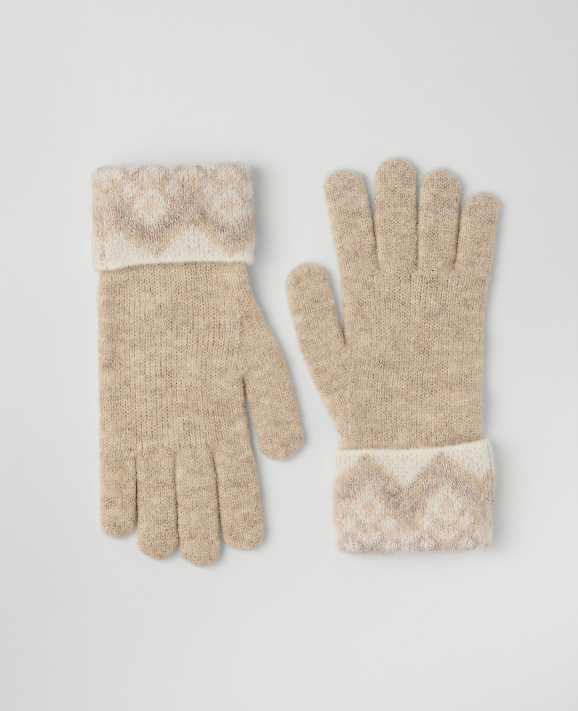A pair of beige knitted gloves with patterned cuffs rests on a plain light gray background.