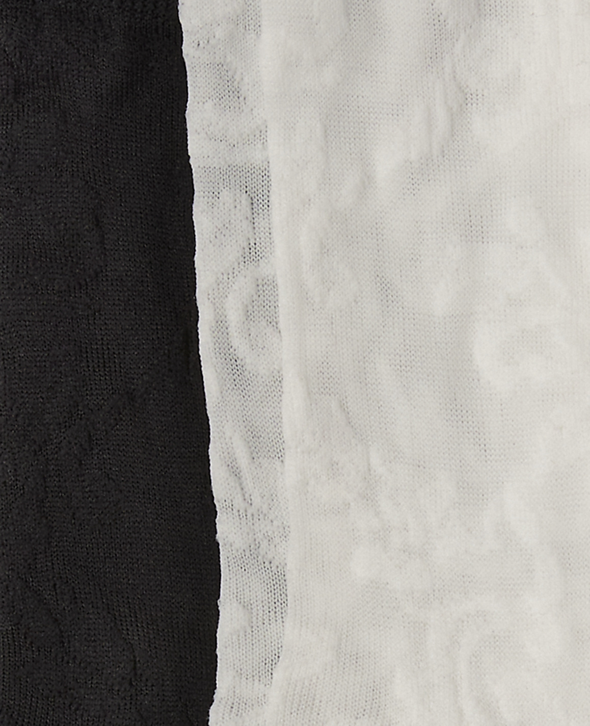 A black textured fabric stands in the foreground against a white textured fabric background.