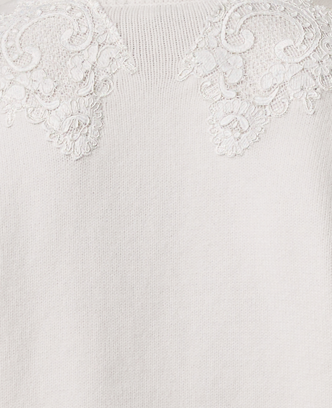 Intricate white lace floral appliqu&eacute;s adorn the neckline of a soft, cream-colored knit fabric.