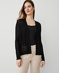 A woman in a black cardigan and beige pants stands against a plain white background. carousel Product Image 1
