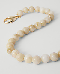 A delicate, creamy beaded bracelet with a gold clasp rests on a plain white background. carousel Product Image 2