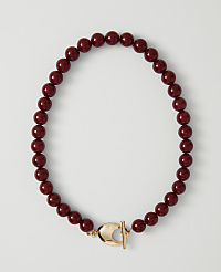 A deep red beaded necklace with a gold clasp lies on a plain white background. carousel Product Image 1