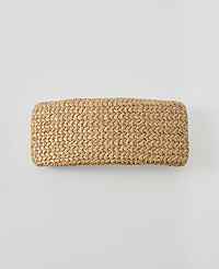 A woven straw clutch rests on a plain, light gray background. carousel Product Image 1