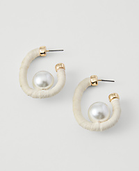 A pair of cream-colored hoop earrings with a pearl accent are displayed against a plain white background. carousel Product Image 1