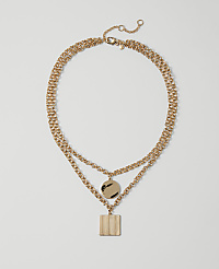 A layered gold necklace with a circular pendant and a square pendant hangs against a plain white background. carousel Product Image 1