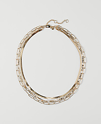 A layered gold necklace with a herringbone chain and rectangular links rests on a plain white background. carousel Product Image 1