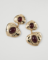 Gold heart-shaped earrings with deep red stones dangle against a plain white background. carousel Product Image 1